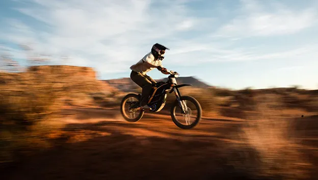 Piloto saltando com uma e-moto 79BIKE no deserto